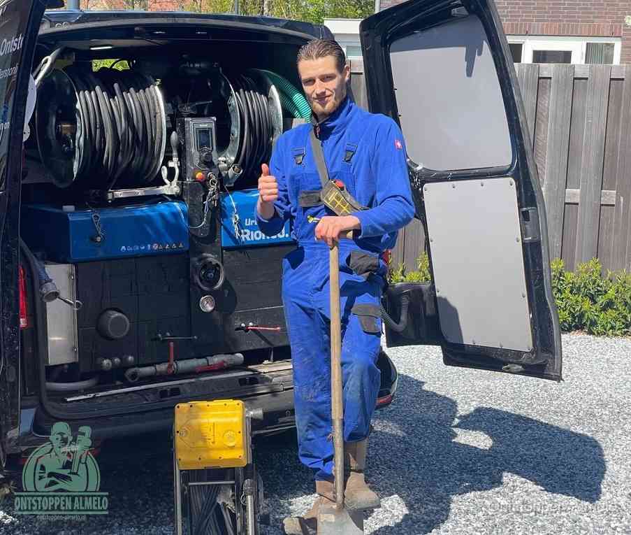 Een tevreden monteur met opgestoken duim naast de bestelbus, slim ingrijpen bespaart kosten bij een verstopte afvoer in Almelo