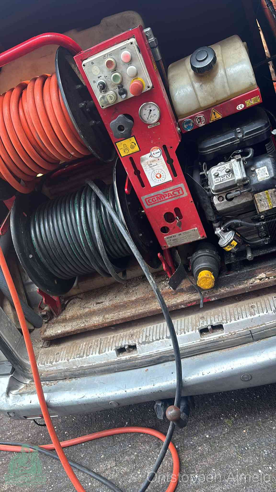 Een rood hogedruk-rioolreinigingstoestel in de laadbak van de bedrijfsbus, apparatuur voor een hardnekkige afvoerverstopping in Almelo