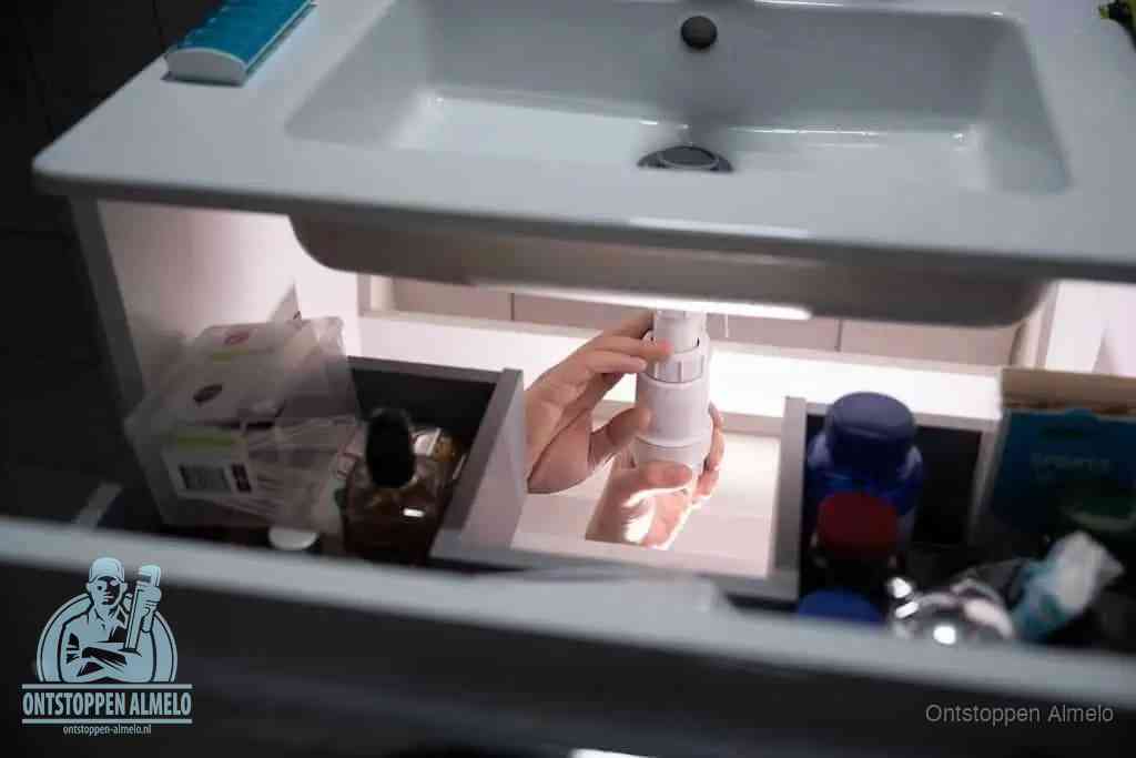 Een pompfles met zeep boven een wastafel in de toiletruimte, de warm water en afwasmiddel-methode om de wc te ontstoppen in Almelo