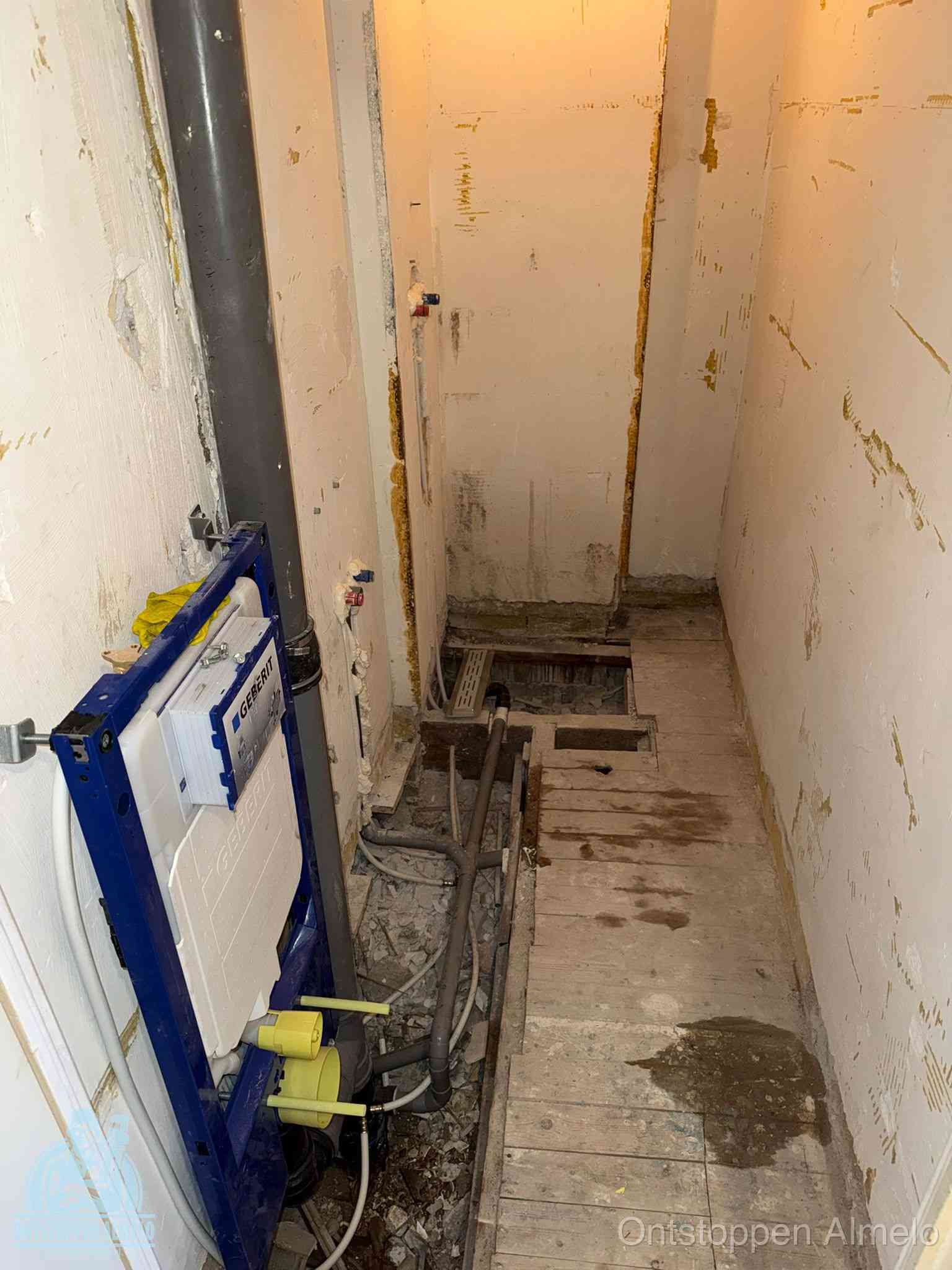 Een opgebroken toiletruimte tijdens renovatie met een Geberit inbouwreservoir en blootliggende oude afvoerleidingen, typisch voor oudere woningen in Almelo